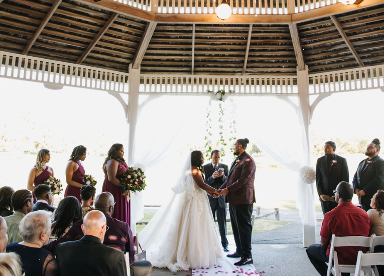 Wedding party standing before officaint under the gazebo