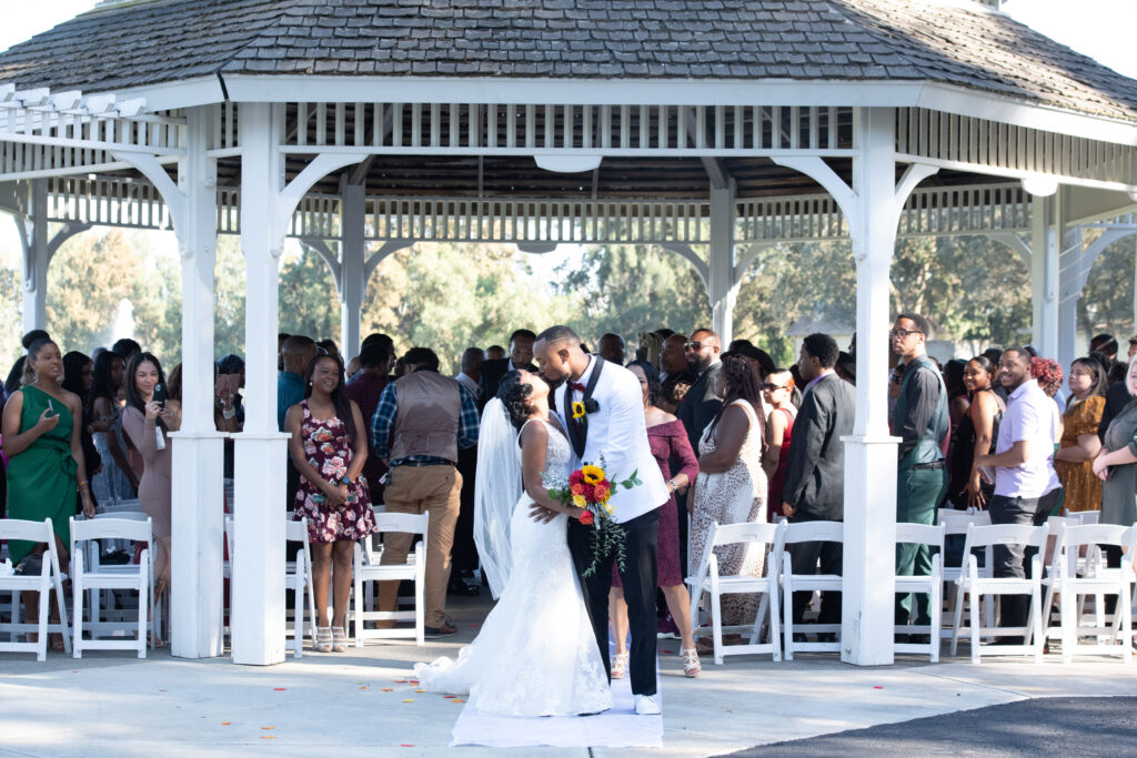 Bride and Groom kissing at the end of the aisle in gazebo